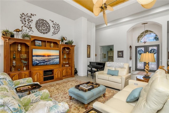 living room featuring tile patterned floors, ceiling fan, french doors, and a towering ceiling