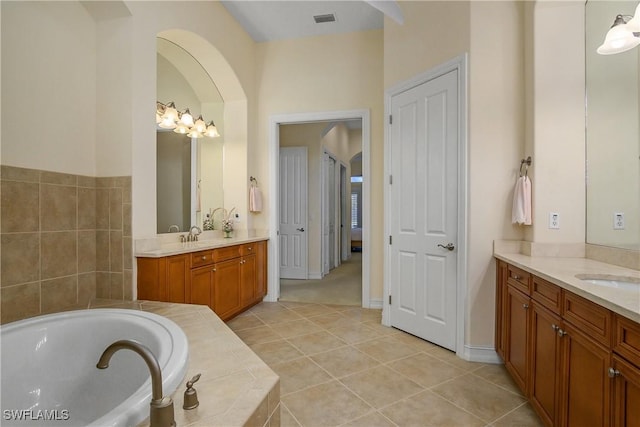 bathroom with two vanities, tile patterned flooring, visible vents, and a garden tub