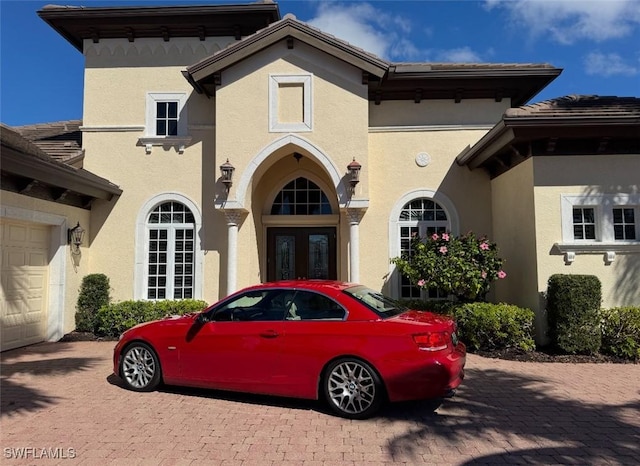 view of front facade with a garage, french doors, and stucco siding