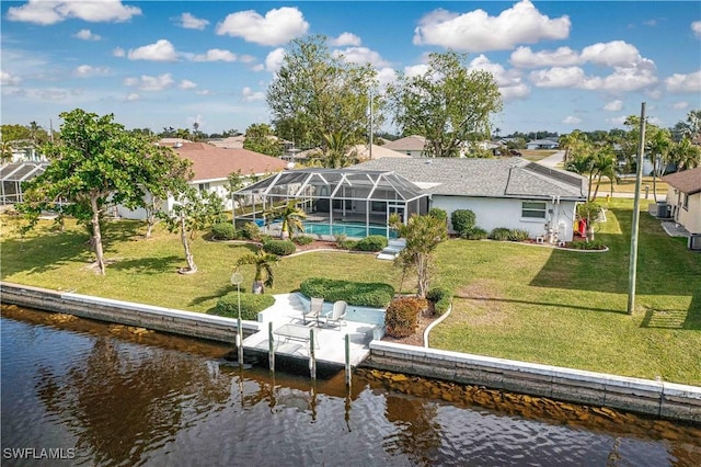 back of property featuring a lanai, a lawn, and a water view