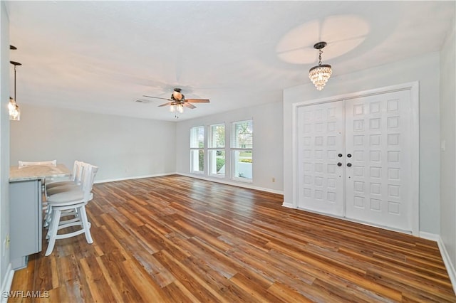 entrance foyer featuring ceiling fan with notable chandelier and dark wood-type flooring