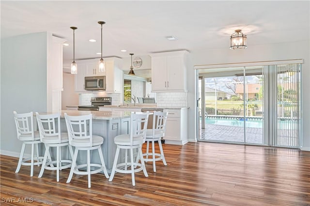 kitchen featuring decorative backsplash, white cabinetry, stainless steel appliances, and dark hardwood / wood-style floors