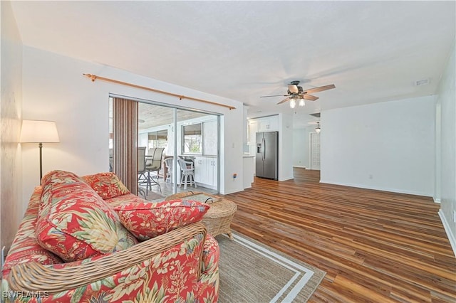 living room featuring ceiling fan and dark hardwood / wood-style flooring