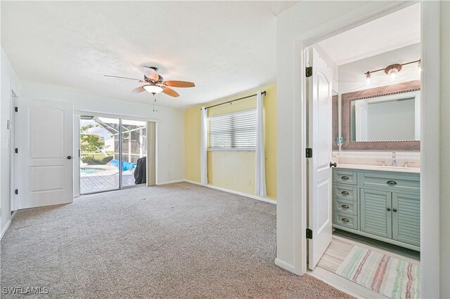 interior space with light carpet, sink, and ceiling fan