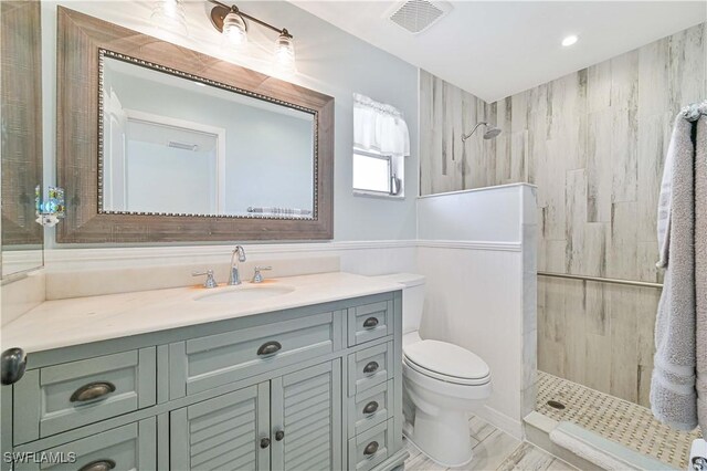 bathroom featuring vanity, toilet, and a tile shower