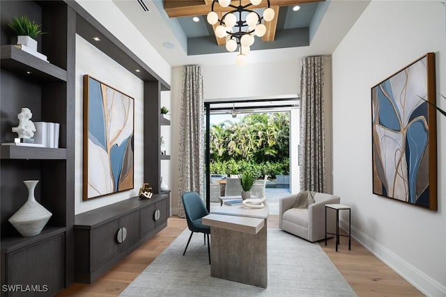 office area with light wood-type flooring, a tray ceiling, and an inviting chandelier