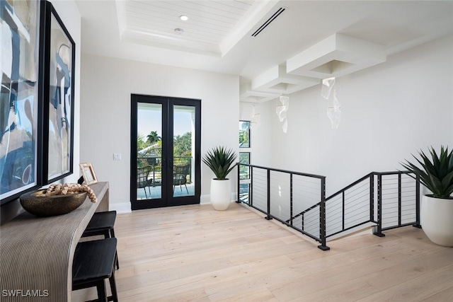 foyer featuring a raised ceiling, french doors, and light hardwood / wood-style flooring