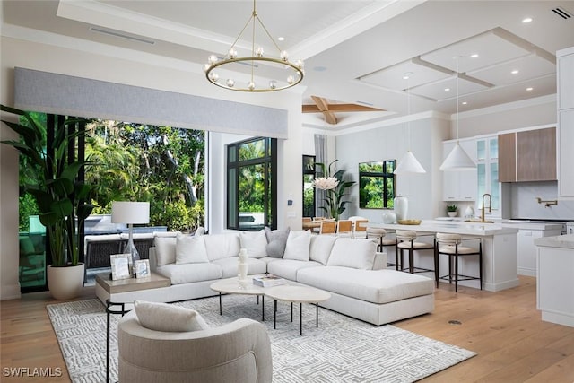 living room featuring crown molding, an inviting chandelier, coffered ceiling, and light wood-type flooring