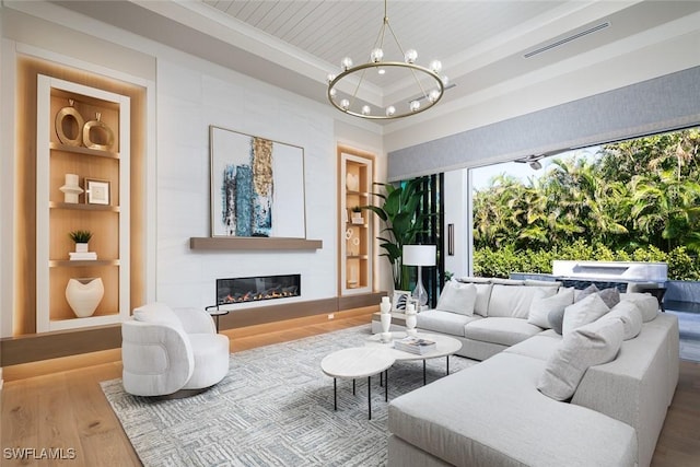 living room with hardwood / wood-style floors, an inviting chandelier, a tray ceiling, a large fireplace, and wood ceiling