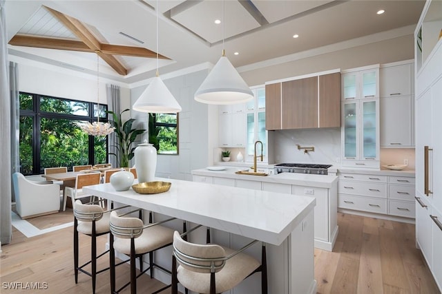 kitchen featuring tasteful backsplash, pendant lighting, white cabinets, a center island, and light hardwood / wood-style floors