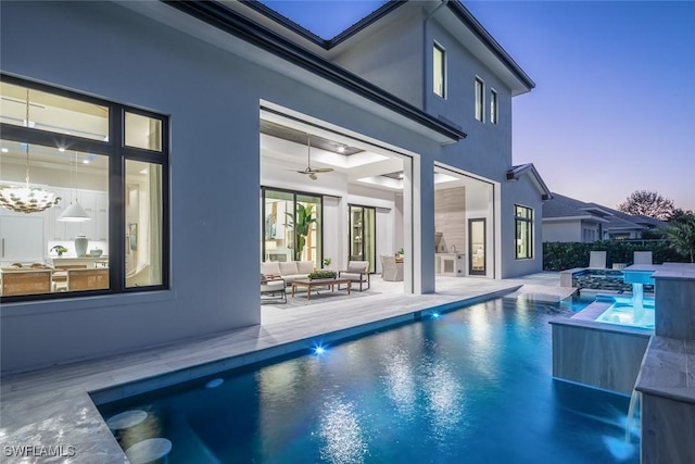 pool at dusk featuring an outdoor hangout area, a patio area, pool water feature, and a hot tub