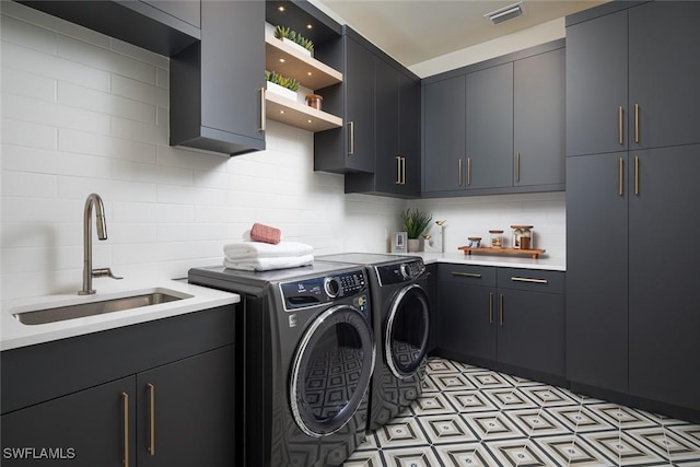 washroom with cabinets, independent washer and dryer, and sink