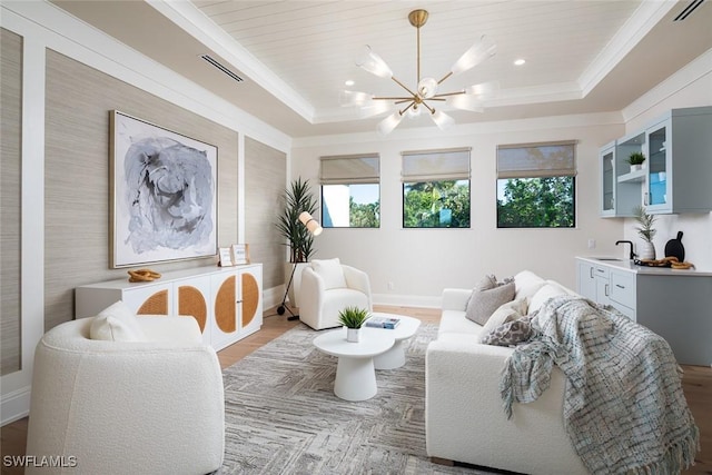 living room with a raised ceiling, plenty of natural light, and a notable chandelier