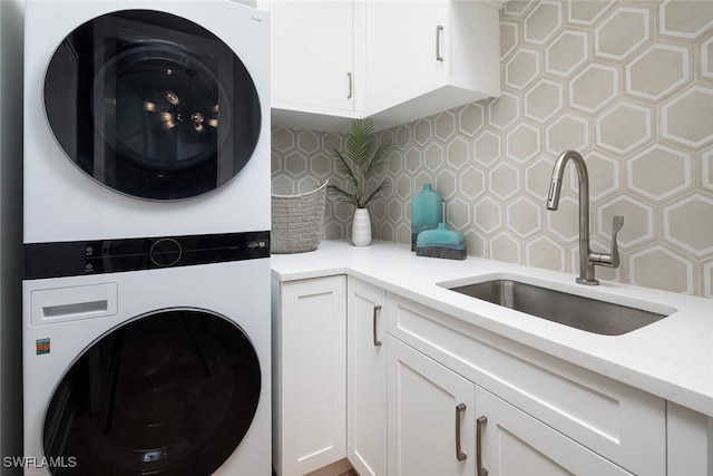 laundry area featuring sink, cabinets, and stacked washer / drying machine