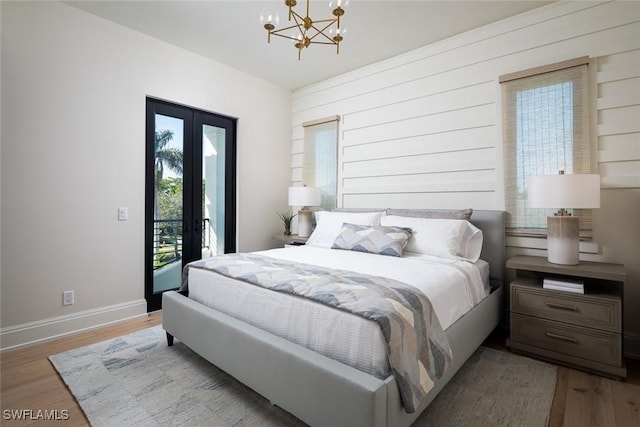 bedroom featuring access to outside, an inviting chandelier, and hardwood / wood-style flooring