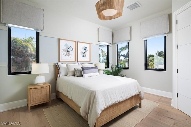 bedroom with multiple windows and light hardwood / wood-style floors