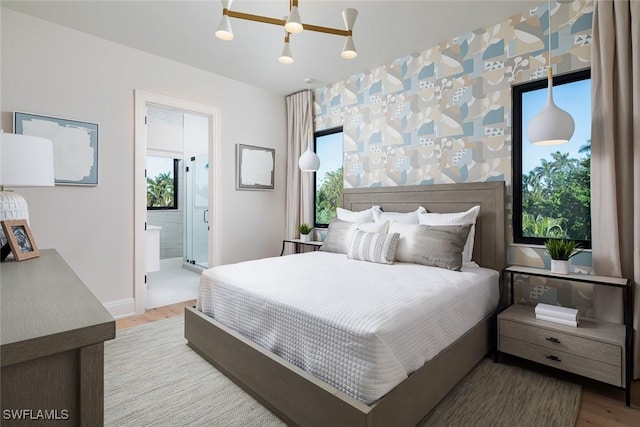 bedroom with ensuite bath, a chandelier, and wood-type flooring