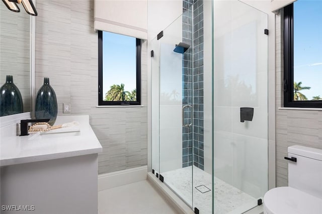 bathroom featuring a wealth of natural light, vanity, an enclosed shower, and toilet