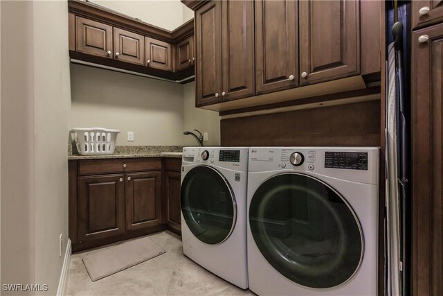 washroom featuring separate washer and dryer, sink, light tile patterned floors, and cabinets