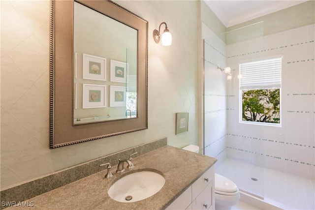 bathroom with vanity, toilet, and tiled shower