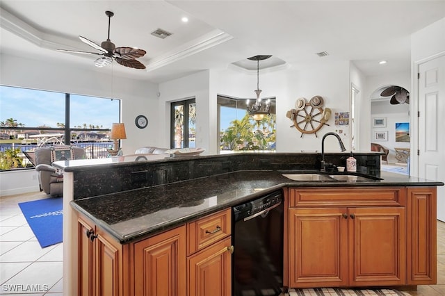 kitchen featuring pendant lighting, dark stone counters, a raised ceiling, sink, and black dishwasher