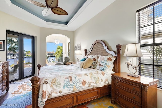 bedroom featuring access to outside, french doors, ceiling fan with notable chandelier, a water view, and hardwood / wood-style flooring