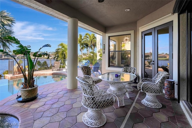 view of patio / terrace featuring french doors, a fenced in pool, and a water view