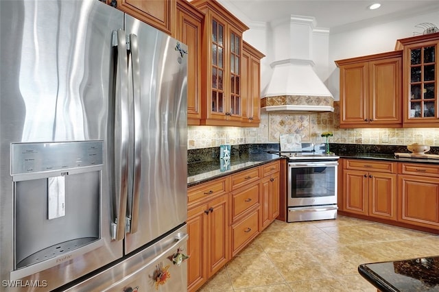 kitchen with premium range hood, dark stone countertops, crown molding, and appliances with stainless steel finishes