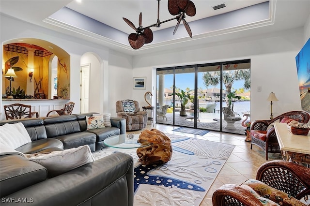 living room with a water view, a raised ceiling, ceiling fan, and light tile patterned flooring