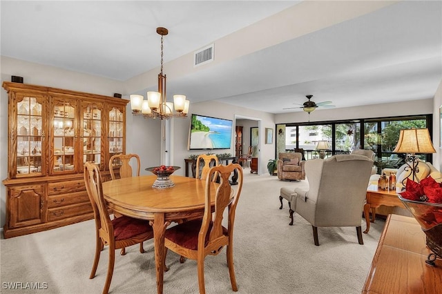 carpeted dining space featuring ceiling fan with notable chandelier