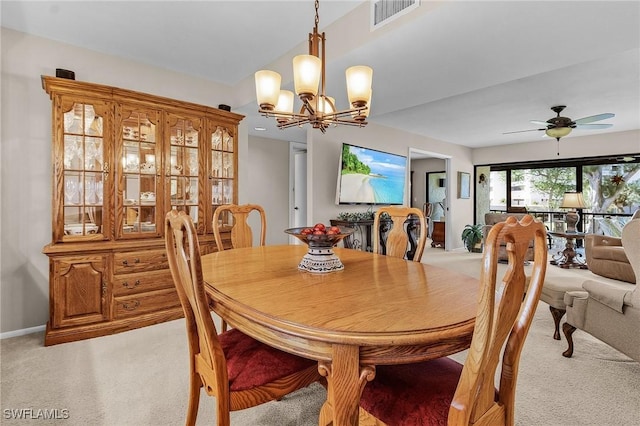 carpeted dining space with ceiling fan with notable chandelier