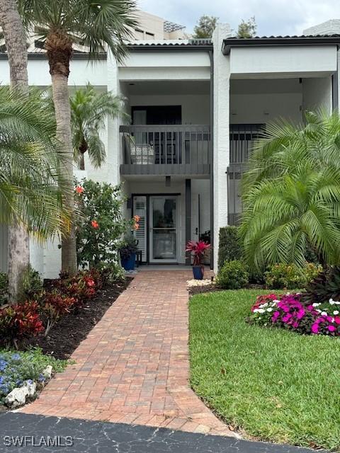 view of exterior entry featuring a lawn and a balcony