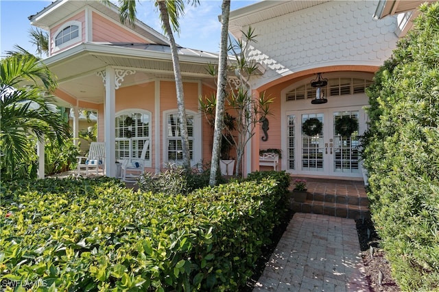 view of exterior entry featuring french doors and a porch