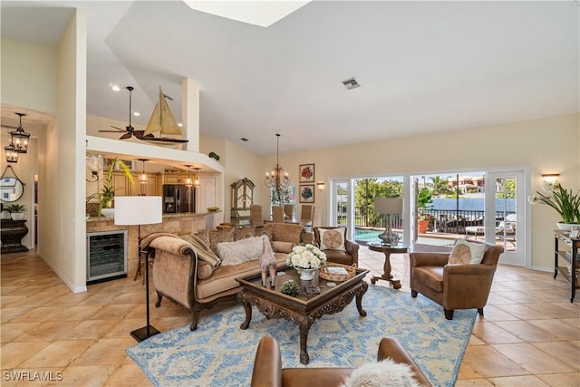 living room featuring ceiling fan with notable chandelier, high vaulted ceiling, beverage cooler, and light tile patterned flooring