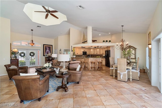 living room with ceiling fan with notable chandelier, high vaulted ceiling, and french doors