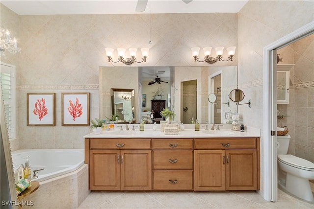 bathroom with vanity, tiled tub, tile walls, tile patterned flooring, and toilet