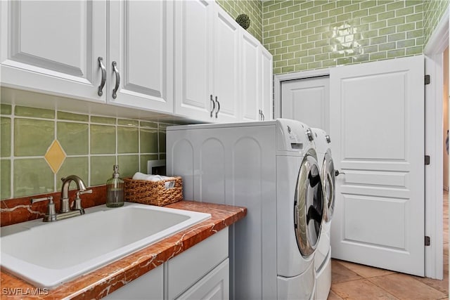 laundry area featuring separate washer and dryer, sink, light tile patterned floors, and cabinets