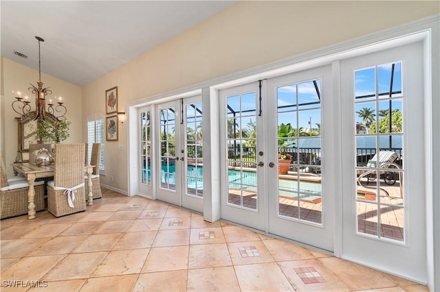 entryway featuring french doors, light tile patterned flooring, and a notable chandelier