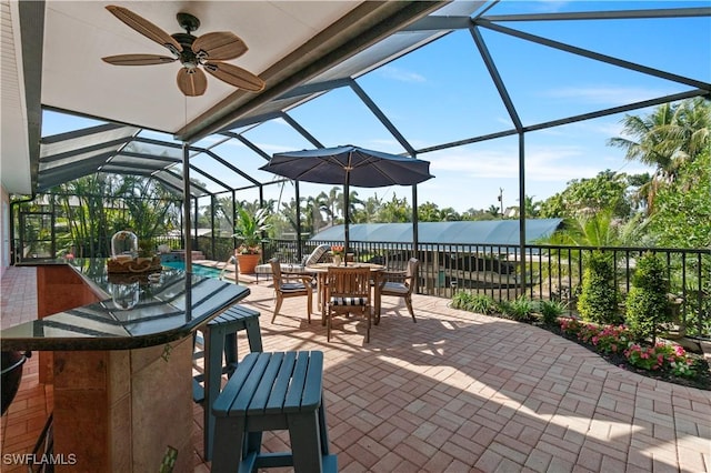 view of patio featuring glass enclosure, an outdoor bar, and ceiling fan