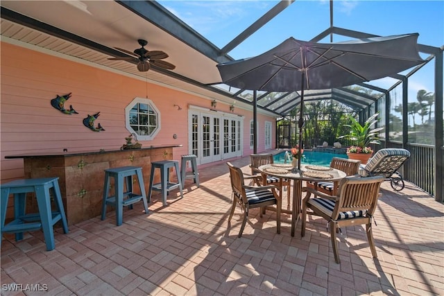 view of patio / terrace featuring glass enclosure, ceiling fan, french doors, and an outdoor bar