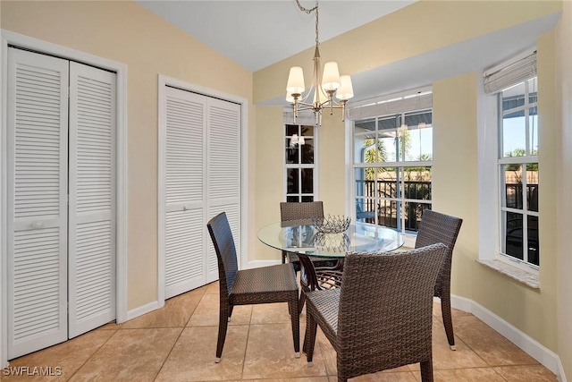 dining area featuring light tile patterned floors, vaulted ceiling, and an inviting chandelier