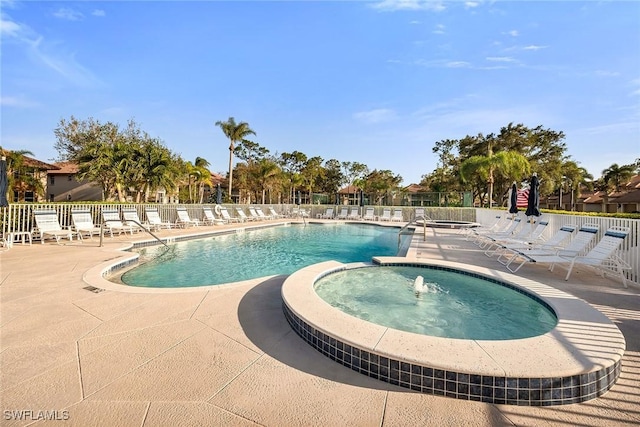 view of pool featuring pool water feature, a patio, and a hot tub