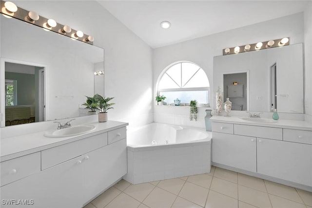 bathroom featuring vanity, tile patterned floors, a wealth of natural light, and tiled tub