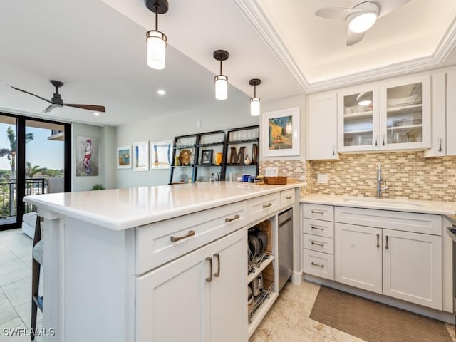 kitchen with kitchen peninsula, tasteful backsplash, sink, pendant lighting, and white cabinets