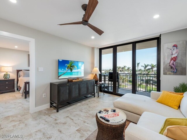 living room with ceiling fan and a wall of windows