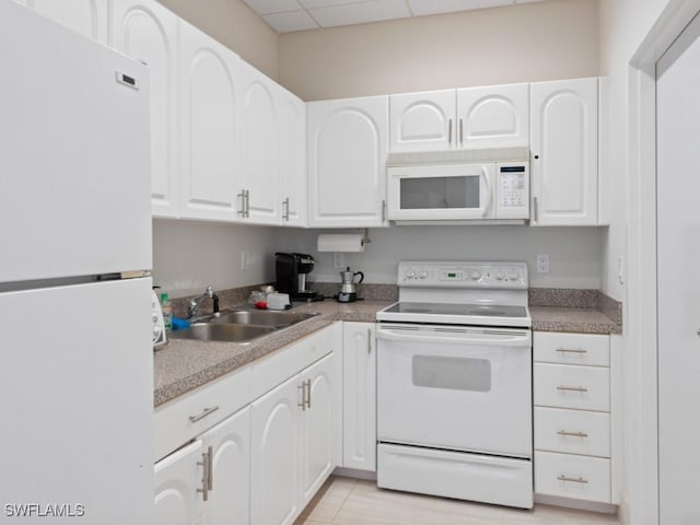 kitchen with white cabinets, a drop ceiling, white appliances, and sink