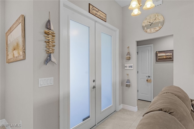 entrance foyer featuring a notable chandelier, light tile patterned floors, and french doors