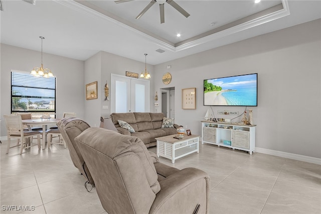 living room with light tile patterned floors, ceiling fan with notable chandelier, a tray ceiling, and crown molding