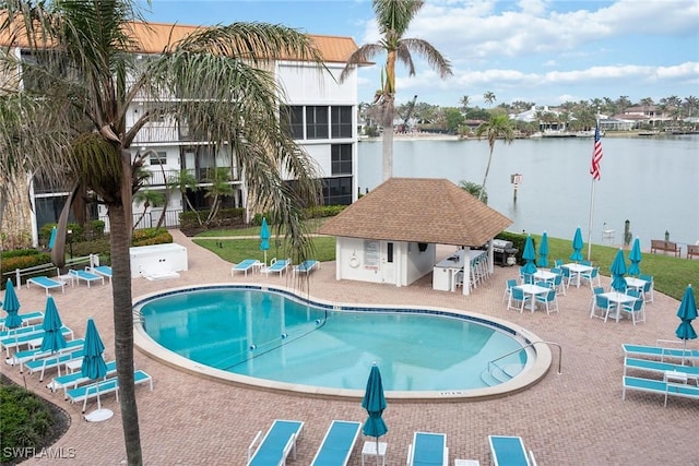 view of swimming pool featuring an outdoor structure, a water view, and a patio area