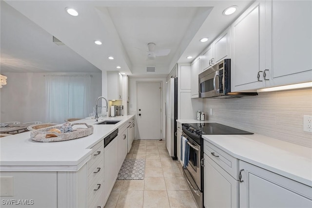 kitchen with backsplash, sink, appliances with stainless steel finishes, light tile patterned flooring, and white cabinetry